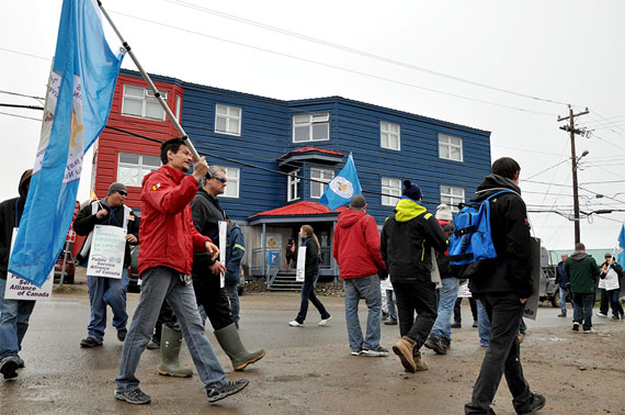 Striking workers wave flags and chant slogans outside the Qulliq Energy Corp.'s building in Iqaluit on the morning of July 16. QEC employees, who have been without a contract since Dec. 31, 2013, began the strike and set up picket lines just after midnight July 16. (PHOTO BY THOMAS ROHNER)
