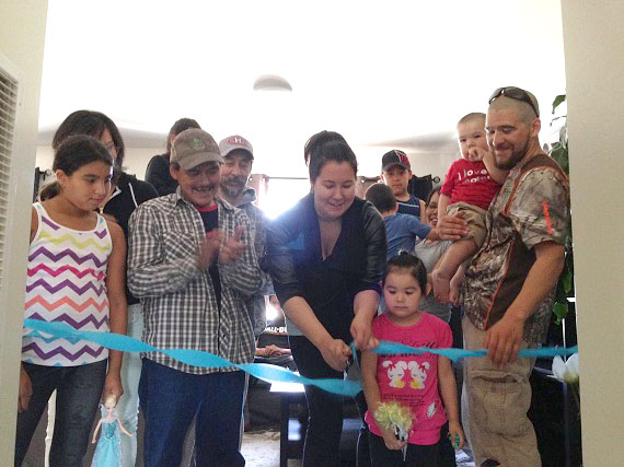 Nikita Etok, centre, cuts the ribbon at the entry of her newly made-over home Aug. 9, accompanied by her partner, Jimmy Chevrier, right, and her two children Anjali, 4 and Jayden 1. (PHOTO COURTESY OF PIVALIANIQ) 