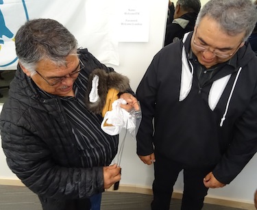 Stanley Anablak, the president of the Kitikmeot Inuit Association, examines a necklace made of ivory and baleen given to him by Jobie Tukkiapik, the president of Makivik. Corp., for hosting the Inuit Tapiriit Kanatami annual general meeting at the KIA's Fred Elias office building in Cambridge Bay. Other gifts brought by delegates to the ITK AGM included a carving from Nunatsiavut, T-shirts from the National Inuit Youth Council and country foods from the Inuvialuit Regional Development Corp. (PHOTO BY JANE GEORGE)