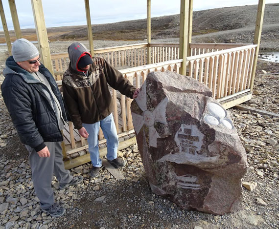 Cambridge Bay SAO Stephen King stands with hamlet employee Kevin Taylor at the Truth and Reconciliation park right outside Cambridge Bay. As Taylor, who etched the stone in his spare time explains, its design is meant to honour former residential school students as well as Cambridge Bay's history, culture and people: children, parents and grandparents (three circles to the right), the familiar Loran Tower, now torn down, an inuksuk and a seaplane. The park, a hamlet project, called 