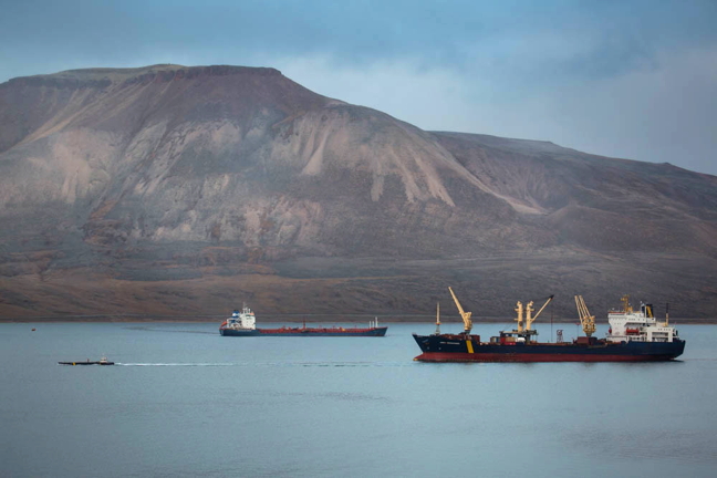 The tiny M/V Wave, the red dot to the far left in this photo, fresh from transversing the Northwest Passage, shares anchorage in Arctic Bay with the Woodward Group fuel ship, M/V Travestern, and the sealift supply ship, M/V Anna Desgagnés, seen here sending one of its barges ashore. Summer is a busy time for Nunavut's coastal communities but soon those watery havens will be covered in ice. (PHOTO BY CLARE KINES)