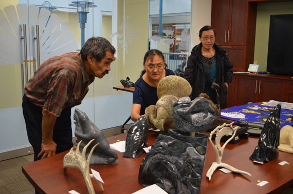 Directors and executives of Nunavik's Fédération des Coopératives du Nouveau-Québec, or Ilagiisaq, take a moment to view and judge the pieces of art submitted to the FCNQ's 2015 carving contest. That was one of the events held as part of FCNQ meetings in Montreal last week. A first place prize of $2,500 was awarded to Aupaluk artist Johnny Akpahatak for his carving on a polar bear sneaking up on a resting walrus. (PHOTO COURTESY OF THE FCNQ) 

