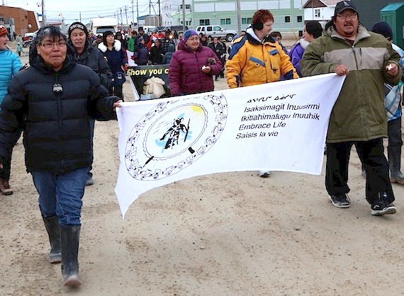Two marchers in Cambridge Bay, carrying an Embrace Life banner and small candles, lead the way for others in an event held Sept. 10, 2013 to mark World Suicide Prevention Day. In 2015, 32 Nunavut residents died by suicide, the Office of the Chief Coroner said. (FILE PHOTO)