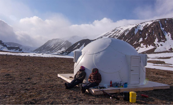 Visitors to Kuurujuaq park rest outside their igloo-shaped shelter along the Koroc River valley. A number of different travel packages offer the chance to visit the park on snowshoes, snowmobile or even by dog team. (PHOTO BY ERIC BOZET/NUNAVIK PARKS)