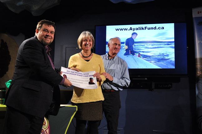 Alain Grenier of Indigenous and Northern Affairs Canada, left, presents Laurie and David Pelly a cheque for more than $1,600 at the Unikkaarvik Visitor's Centre in Iqaluit April 12. The INAC office raised the money for the Ayalik Fund — a charitable organization set up in memory of the Pellys' son, Eric Ayalik who was born in Cambridge Bay and who died suddenly in 2015 of heart failure at 19 years old. The Ayalik Fund sends Nunavut youth to places around Canada and the world to enrich their lives with group, outdoor experiences outside their home territory, David Pelly said. To learn more, you can visit the fund's website at www.ayalikfund.ca. (PHOTO BY THOMAS ROHNER)
