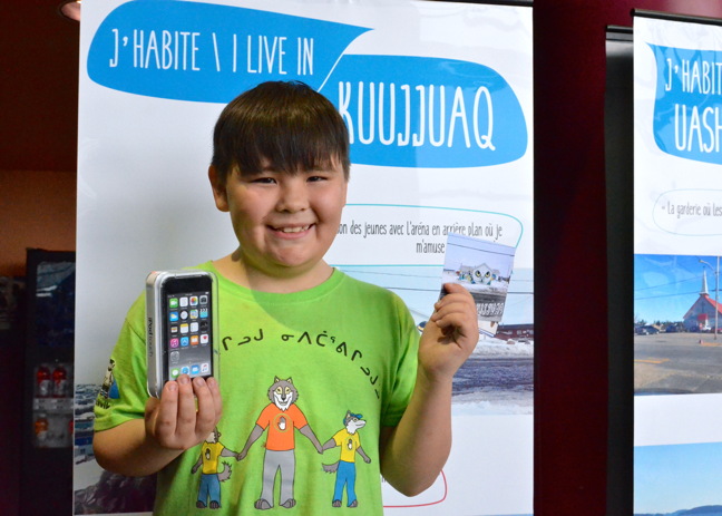 Axel Gordon holds up a postcard made from a photograph he took, and the iPod he won, as part of the J'habite ici/I Live Here photo contest run by Habiter le nord Quebecois/Living in Northern Quebec, a Université Laval research group that studies culturally appropriate design and sustainable development of Nitassinan Innu and Nunavik Inuit communities. The group is holding an Indigenous Northern Housing meeting in Kuujjuaq this week and announced photo contest winners June 7. The contest, open to Grade 5 and 6 students from Innu and Inuit communities including Kuujjuaq and Inukjuak, asked participants to submit photographs that fit the theme
