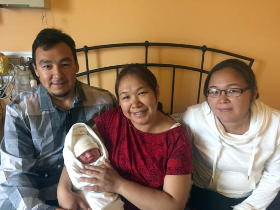 Proud parents Conlucy Niqtairaaluk and mom Leah Unaluk hold newborn Tom Aug. 19 at the maternity centre in Puvirnituq, where he was delivered by midwife Mary Ittukallak, at far right. (PHOTO COURTESY OF A. NAVICKAS)