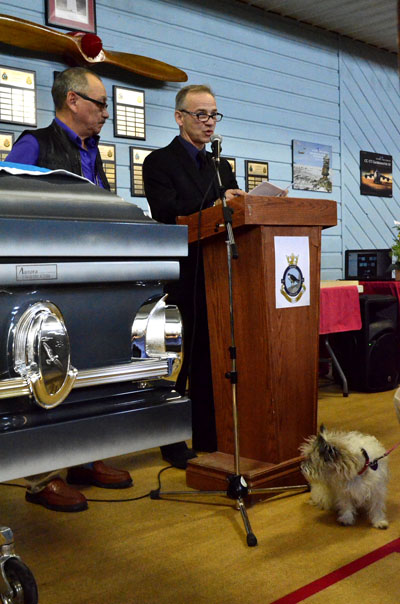 The late Bryan Pearson's old friend, Ed Picco, gives a eulogy at a memorial service for Pearson held Oct. 17 in Iqaluit. In the bottom right corner, Pearson's dog Kamik stands quietly near his late master's coffin. (PHOTO BY JIM BELL)
