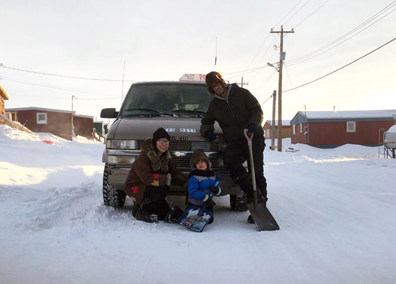 Sherri Lee Mouqtassid with two-year-old Adam and her husband Abdel Mouqtassid in front of one of their taxis Jan. 25. (PHOTO BY MIGUEL UKPAGA)