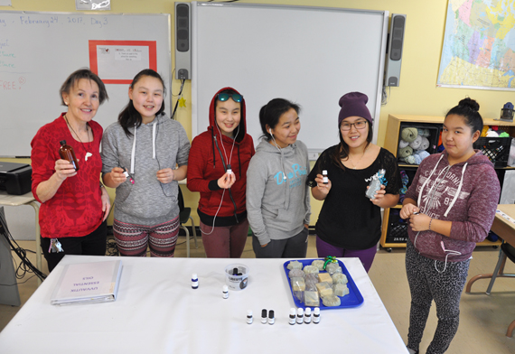 Suzanne Chénard and her Independent Learning Path students at Jaanimmarik high school hold up a fresh batch of their handmade black spruce essential oil. The group’s Girls Project, which started off making handmade soaps, is now producing four types of locally-harvested and distilled essential oils to add scents to the products. In addition to black spruce, the group has also distilled oil from Labrador tea, sweet gale and larch. The Girls Project is looking for support to expand production by setting up a distillation facility at the Kuujjuaq school. (PHOTO BY SARAH ROGERS)