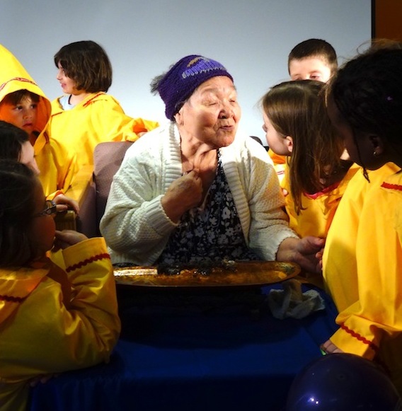 You can call it a kiss, bisou or kunik, but, by any word, you can see a lot of affection between elder Alacie Joamie and students at Ecole des Trois-Soleils at its 15th anniversary celebration April 27. (PHOTO BY JANE GEORGE)