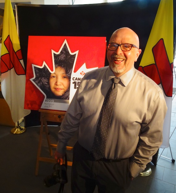 Photographer Clare Kines stands in front of the Nunavut stamp, which features his image of Leah Ejangiaq Kines, his wife, at the May 30 unveiling of the new Canada Post stamp in the Nunavut Legislature's foyer. (PHOTO BY JANE GEORGE)