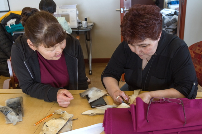 Aytalina Ivanova, left, from Yakutsk, and Clyde River's Jukeepa Hainnu, work on seal skin crafts together. (PHOTO BY ALBERT PANIPAK)