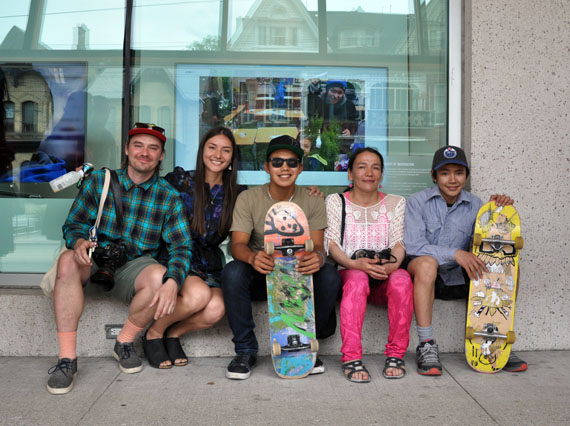 Artists Patrick Thompson, Alexa Hatanaka, Parr Josephie, Alasuak Akesuk and Latch Akesuk sit in front of the Art Gallery of Ontario in Toronto June 28. Behind them, video screens show footage of their group, Embassy of Imagination, and the work behind the group's public murals. Cape Dorset youth will participate in two new mural projects this summer, in Ottawa and in the home community. (PHOTO BY SARAH ROGERS) 