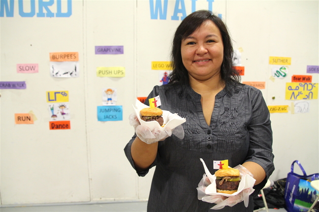 Seal sliders anyone? Eileen Kilabuk hands out some tasty seal, pork and beef mixed sliders, topped with caramelized onions and sweet pickles, and wedged between a deep fried bannock bun. The savoury treats, made by Nunavut's Sheila Lumsden—known for her appearance on CTV's MasterChef Canada—were popular among shoppers and artisans at the Nunavut Arts and Crafts Association's annual craft fair, held on Nunavut Day, July 9, in Iqaluit. The craft fair wrapped up NACA's annual festival and conference in Iqaluit. (PHOTO BY BETH BROWN)