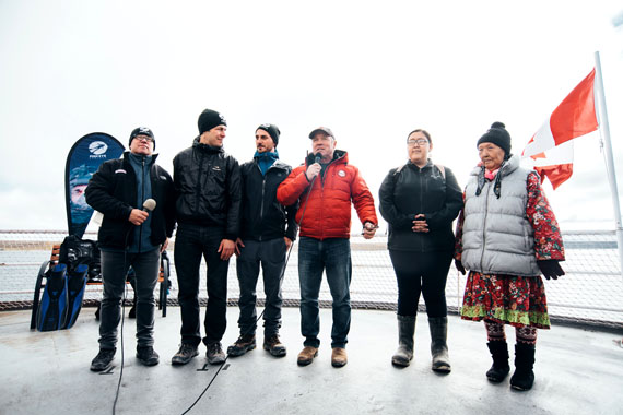 C3 expedition leader Geoff Green speaks during a live broadcast for an underwater Arctic dive led by the ocean education group the Fish Eye Project. Divers and ocean scientists involved are standing to his left, and the Cambridge Bay representative for Ocean Networks Canada Mia Otokiak is to his right, along with Cambridge Bay elder Eva Kakolak. (PHOTO COURTESY OF CANADA C3)