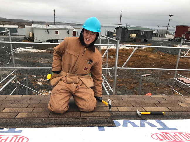 Joe Willie Iqaluk, a Grade 12 student at Paatsaali School in Sanikiluaq, hammers shingles in place on the roof of a new storage shed and garage that students are building as part of a popular school course that teaches skills for employment in trades. School staff tell Nunatsiaq News that students are also building a chicken coop. (PHOTO COURTESY OF PAATSAALI SCHOOL)