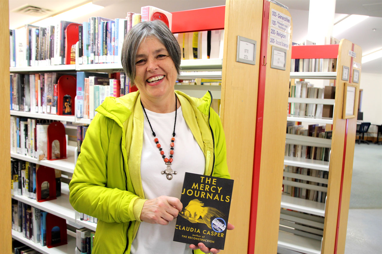 Two new books are available for borrowing at the Iqaluit Centennial Library, thanks to a donation by the award-winning B.C. author, Claudia Casper, who holds a copy of her book, The Mercy Journals. Set in 2048, the book tells a story of a 58-year-old ex-soldier with PTSD. “He’s writing these journals to save himself from being pulled down by the PTSD and to suicide,” Casper said. The novel is set in a post climate change environment, following a global catastrophe where one-third of Earth’s population dies. Casper was in Iqaluit as part of a Vancouver Film School tour during which three young Iqaluit men were selected to attend the academy following auditions. The successful candidates are now eligible to apply for scholarships that Casper helped the school set up for Indigenous youth. The Mercy Journals won the Phillip. K. Dick Award for science-fiction writing, marking the first time a Canadian woman has won the American award. (PHOTO BY BETH BROWN)