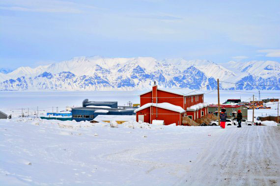 Students get ready to catch a school bus during lunch hour on April 19 in Pond Inlet, while the mountains of Bylot Island provide a formidable backdrop. (PHOTO BY NORMAN KOONOO)
