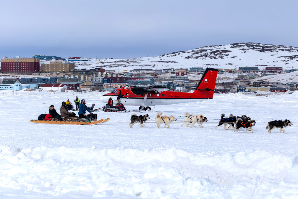 A dogsled team passes a Twin Otter aircraft that had landed on the sea ice outside of Iqaluit on Tuesday, April 18. Kenn Borek Air was practising takeoffs and landings with the ski-mounted plane that day. (PHOTO COURTESY OF BRIAN TATTUINEE)