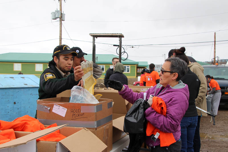Annie Akoak picks up some gloves to use to clean up around her Iqaluit neighbourhood of Legoland on the Apex Road June 22. Iqaluit residents and staff from the city's different organizations were out in full force Friday morning to lend a hand at Iqaluit's 2018 community clean up. (PHOTO BY BETH BROWN)