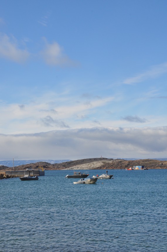 Open-water season is in full swing across much of Nunavut. Boats line the breakwater in Iqaluit, as a barge in the background ferries sealift cargo onto the mainland. (PHOTO BY SARAH ROGERS)