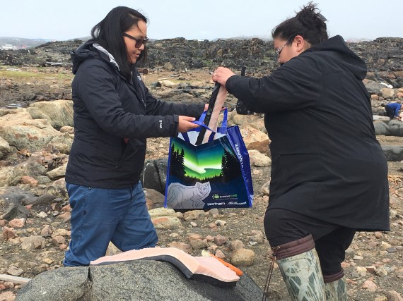Jackie Eegeesiak, left, receives maqtaq earlier today from Koovian Flanagan, one of the harpooners who successfully hunted a bowhead whale near Iqaluit on Tuesday. Eegeesiak planned to bring the prized skin and blubber back to staff at the CanNor office. (PHOTO BY BETH BROWN)