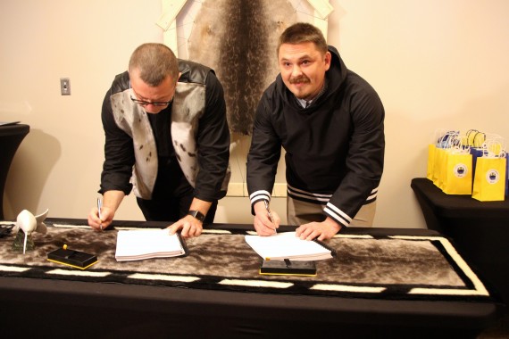 Qikiqtani Inuit Association President P.J. Akeeagok, right, and Baffinland Iron Mines Corp. President Brian Penney sign an amended Inuit impact benefit agreement on Oct. 3 at the Frobisher Inn in Iqaluit. The renegotiated agreement for the Mary River mine prioritizes Inuit employment training and includes a $10-million commitment by Baffinland to see a training centre built in Pond Inlet. (PHOTO BY BETH BROWN)  