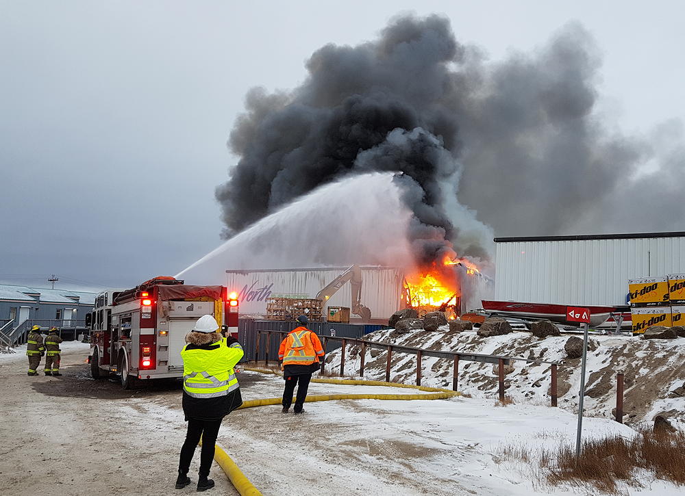 Iqaluit firefighters battle a fire inside the Northmart building on the morning of Thursday, Nov. 8. Here you can see heavy equipment being used to break open the building to help expose the fire. (PHOTO BY SARAH ROGERS)