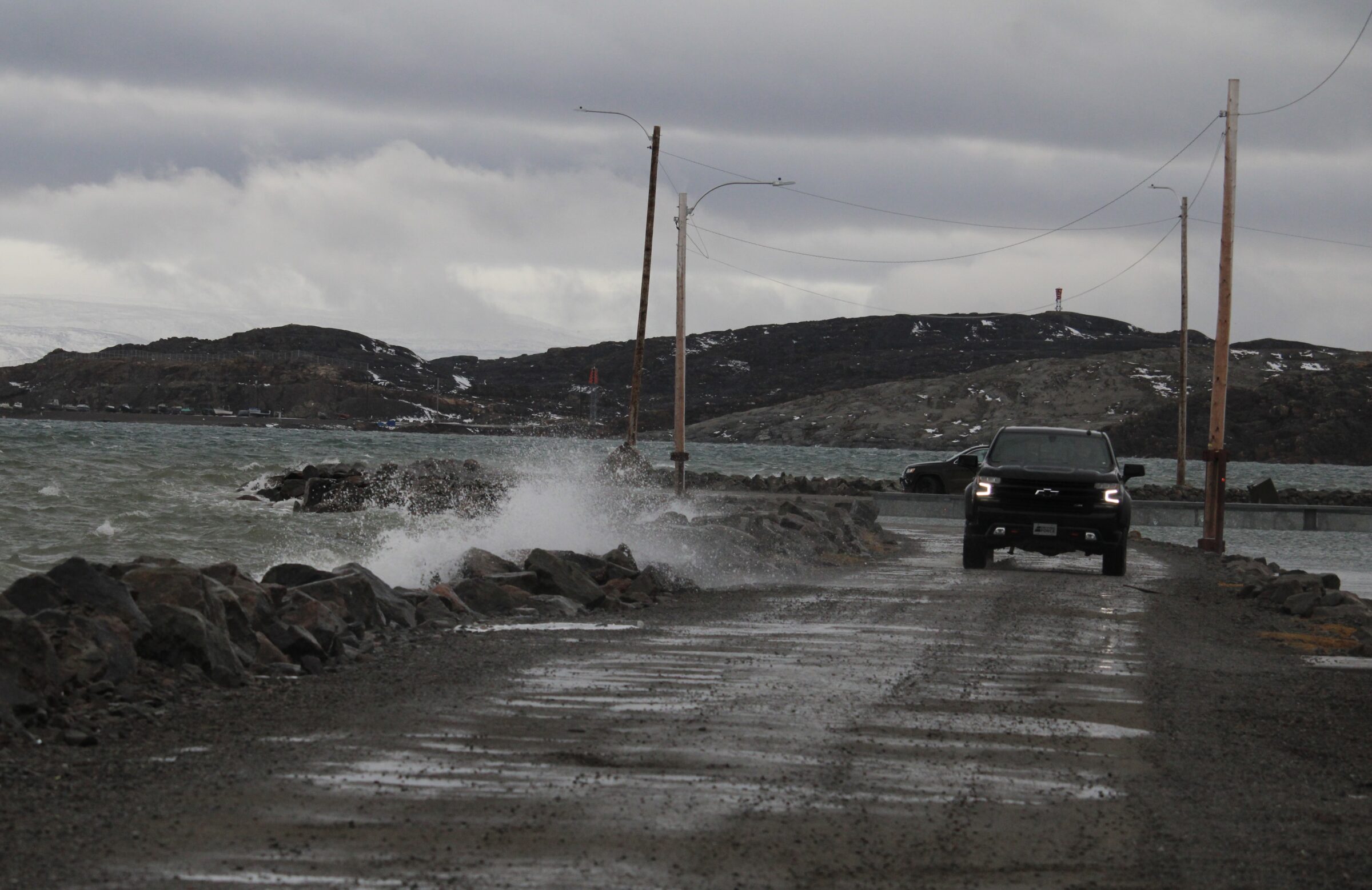 A vehicle drives by the waterfront Friday morning during a storm surge that brought tides as high as they could be without covering the road. Environment Canada issued a storm surge alert on Thursday, warning of higher-than-normal tide waters and possible flooding of ground level spaces on Friday morning. (Photo by Arty Sarkisian)