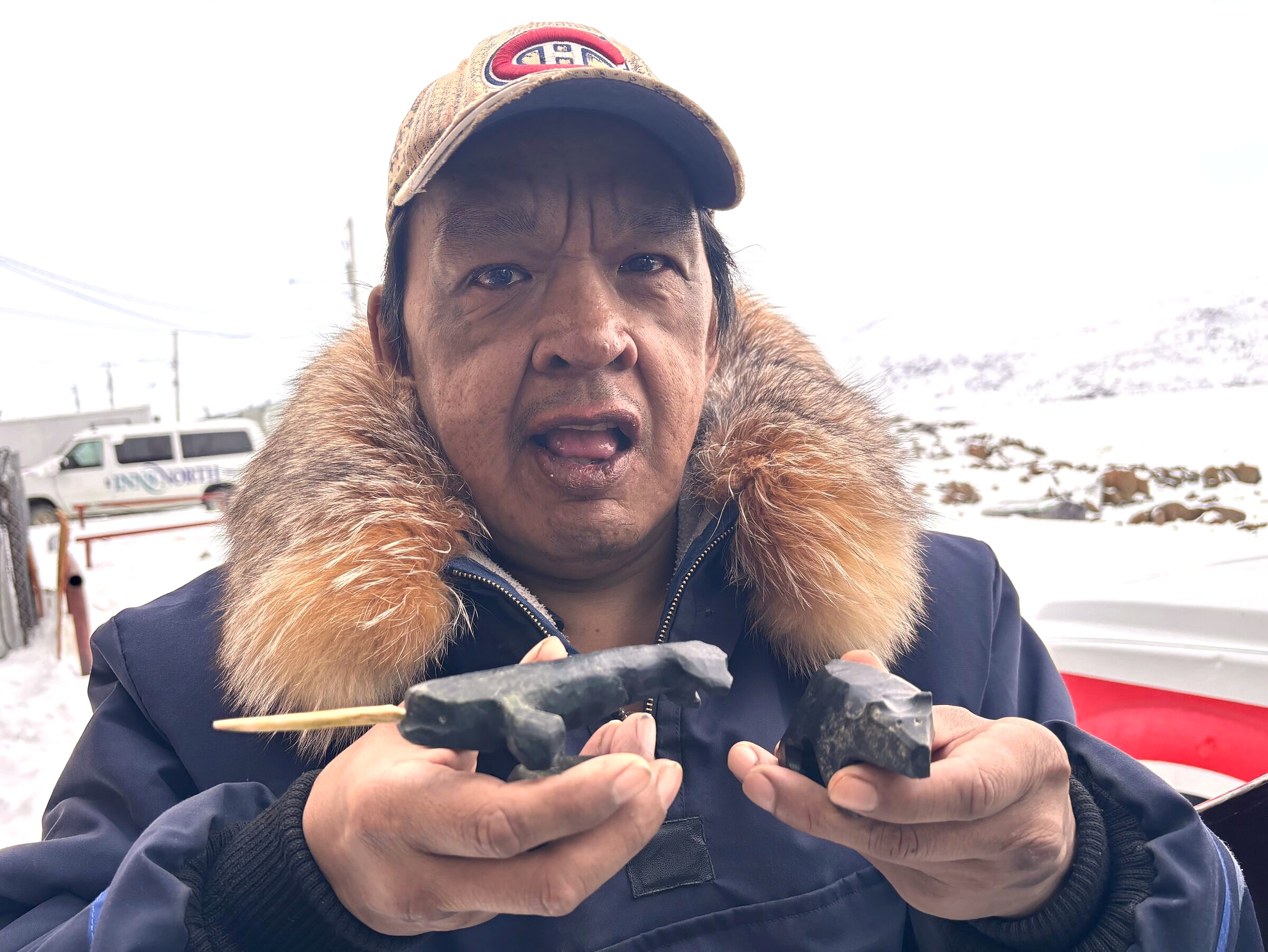 Johnny Veevee sells his carvings of narwhal and other wildlife to visitors at the Pangnirtung waterfront recently. (Photo by Daron Letts)