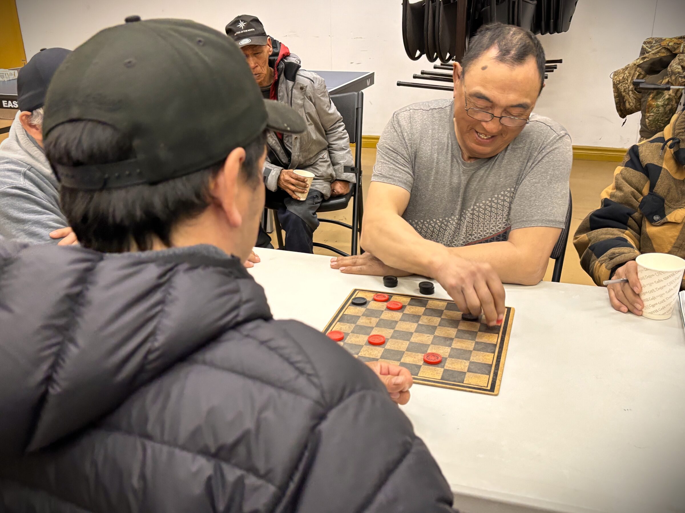 Stevie Karpik takes a red piece from opponent Ricky Kilabuk during a game of checkers Monday evening at the Pangnirtung community centre. Karpik ended up winning the game. Approximately a dozen hunters come out six nights a week to play checkers at the venue, although anybody is welcome to join. (Photo by Daron Letts)
