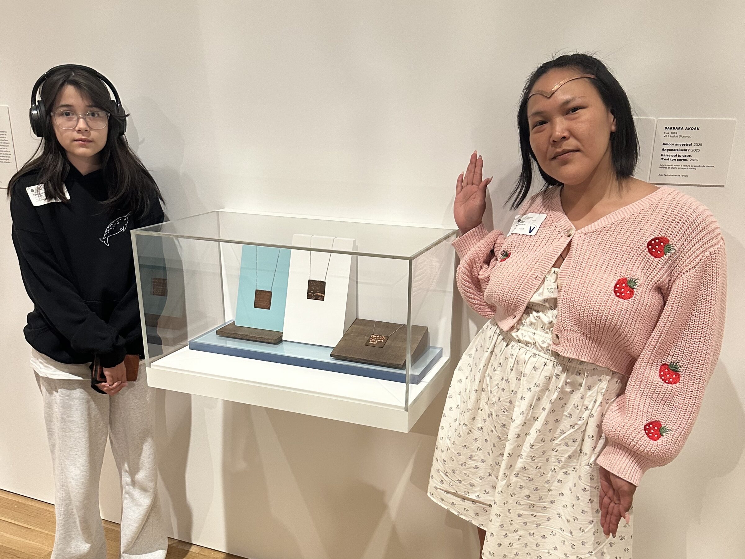 Iqaluit-based artist Barbara Akoak, right, stands beside three oxidized copper pendants with her child Percy Akoak, on June 11. The pendants, which Akoak made, are featured in the Qillaniq exhibition of circumpolar art at the National Gallery of Canada in Ottawa. Titled Ancestral Love; Angunatsiuviit?, or “Are you a hunter?”; and F*ck who you want, It’s your body, the works reflect themes of consent, bodily autonomy and Inuit culture. “To be among so much talent — people for whom this is also their full-time job, or what they’re naturally gifted at — I was so emotional and so proud,” Akoak said. (Photo courtesy of Barbara Akoak)